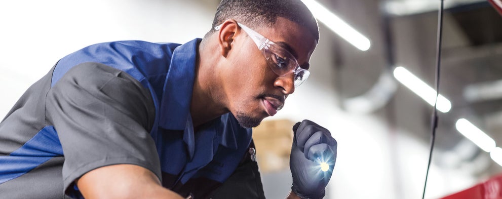 A Subaru technician using flashlight to look into a Subaru engine compartment. | Dalton Subaru National City in National City CA