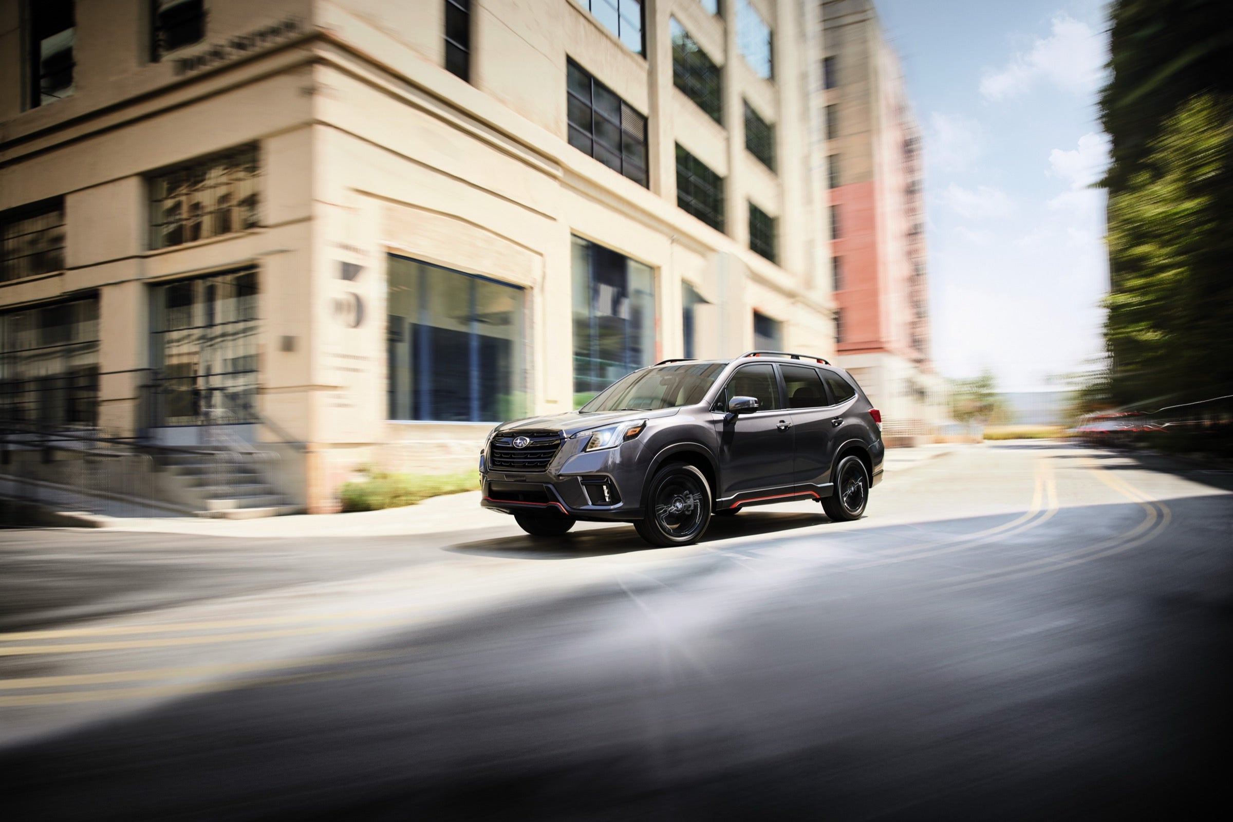 Gray Subaru Forester Sport driving through a city street corner, the kind of pre-owned Subaru sold at Dalton Subaru National City