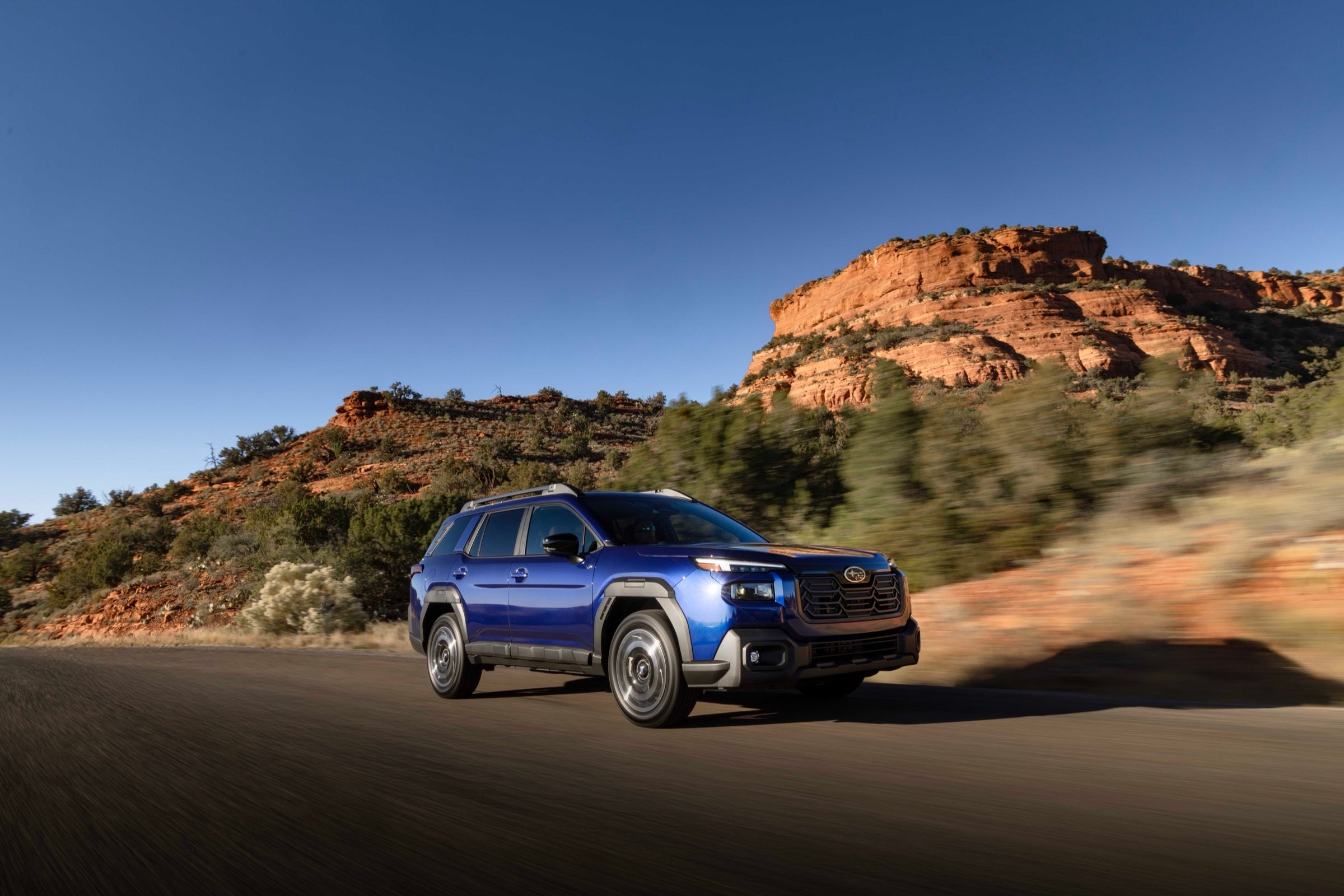 Blue 2026 Subaru Outback driving a red-rock canyon road, the kind of Subaru compared across Limited and Premium trims at Dalton Subaru National City
