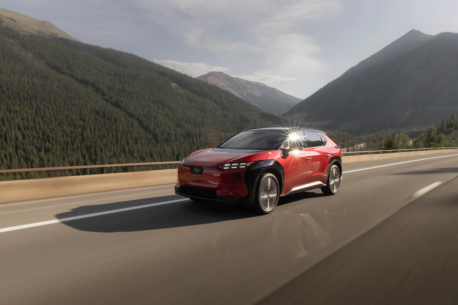 A red Subaru Solterra on a mountain highway.