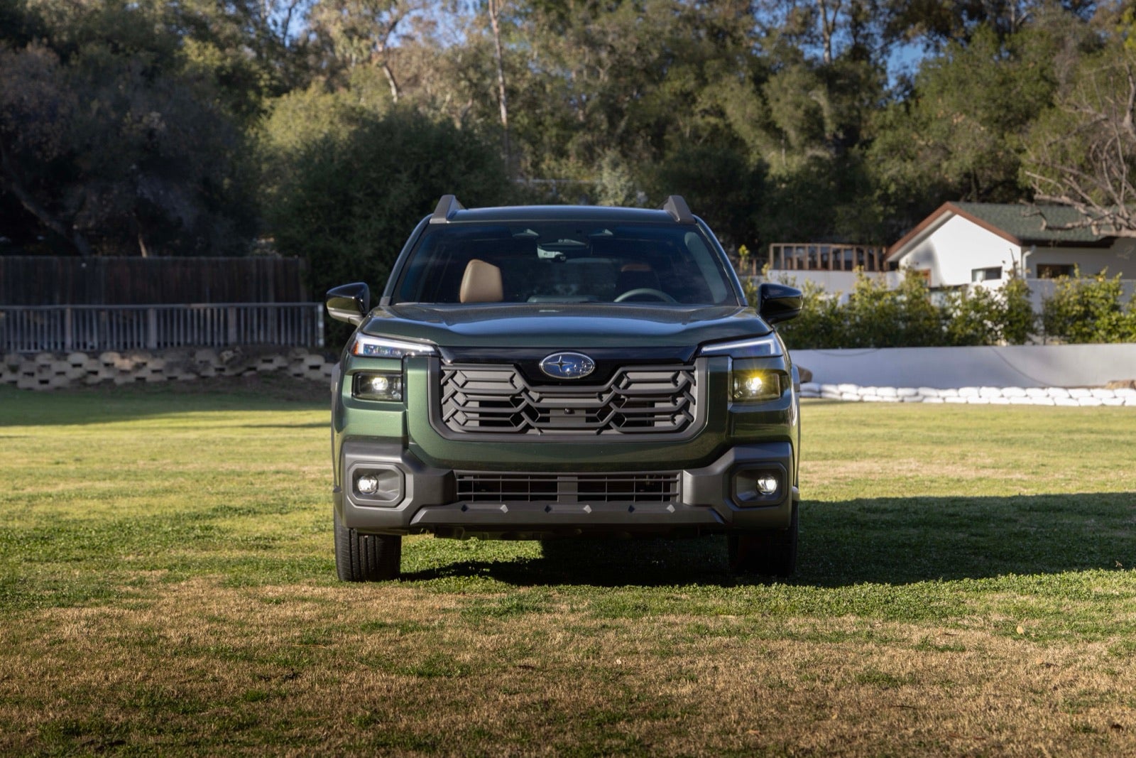 A green 2026 Subaru Outback parked on grass, seen from the front.