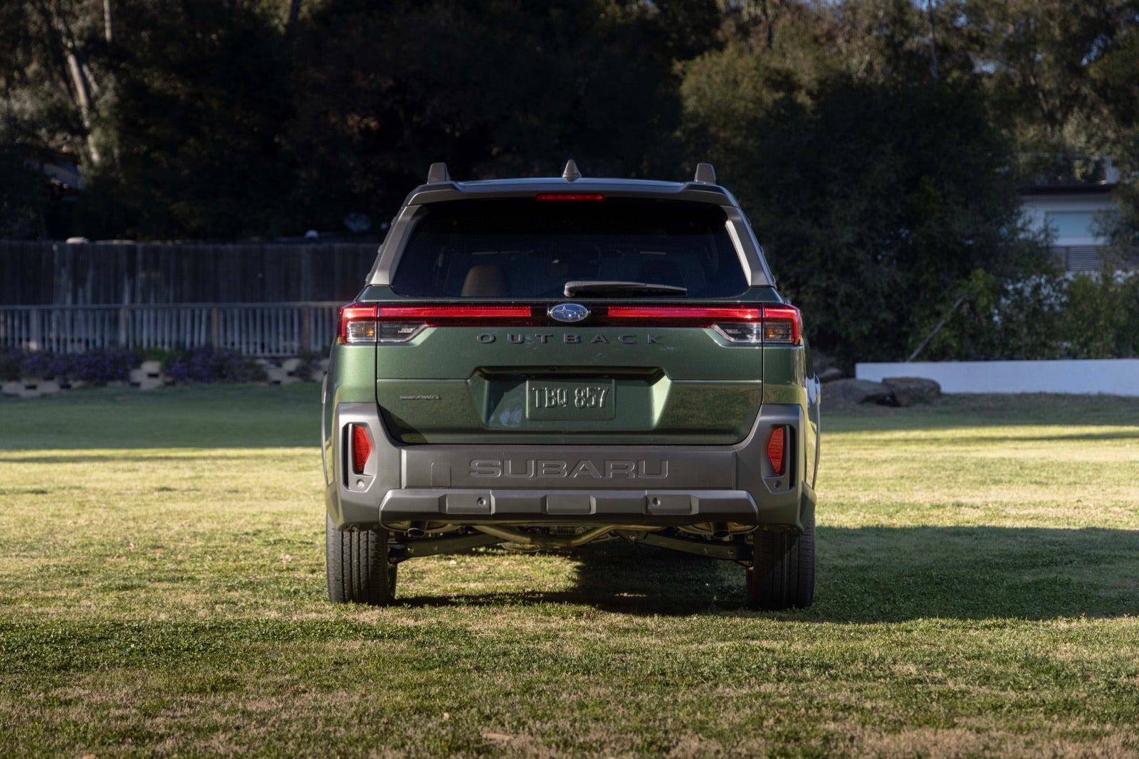 A green 2026 Subaru Outback seen from behind on a lawn.