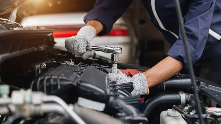 A technician working on an engine with a ratchet.