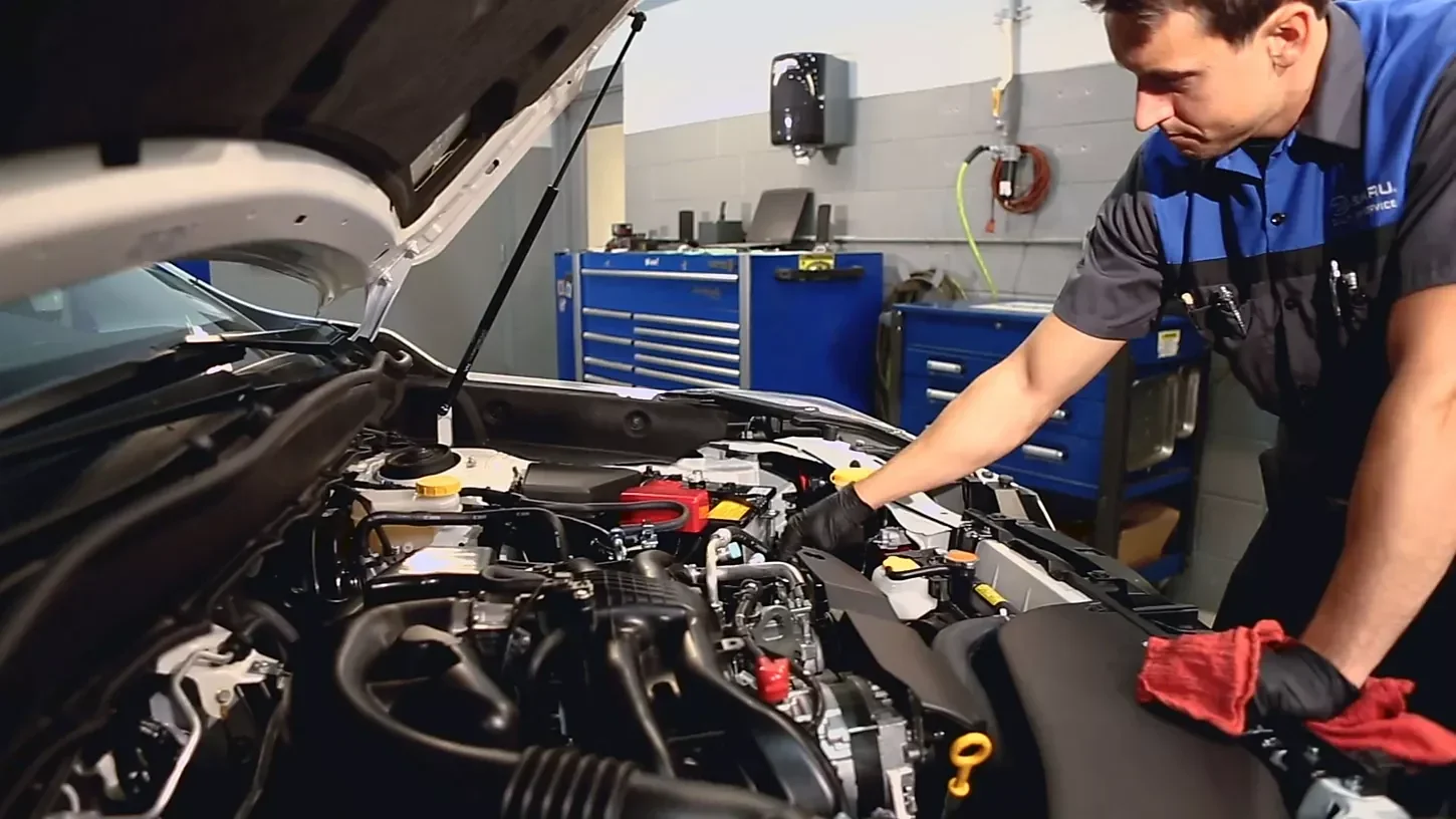 A Subaru technician working in the engine bay.