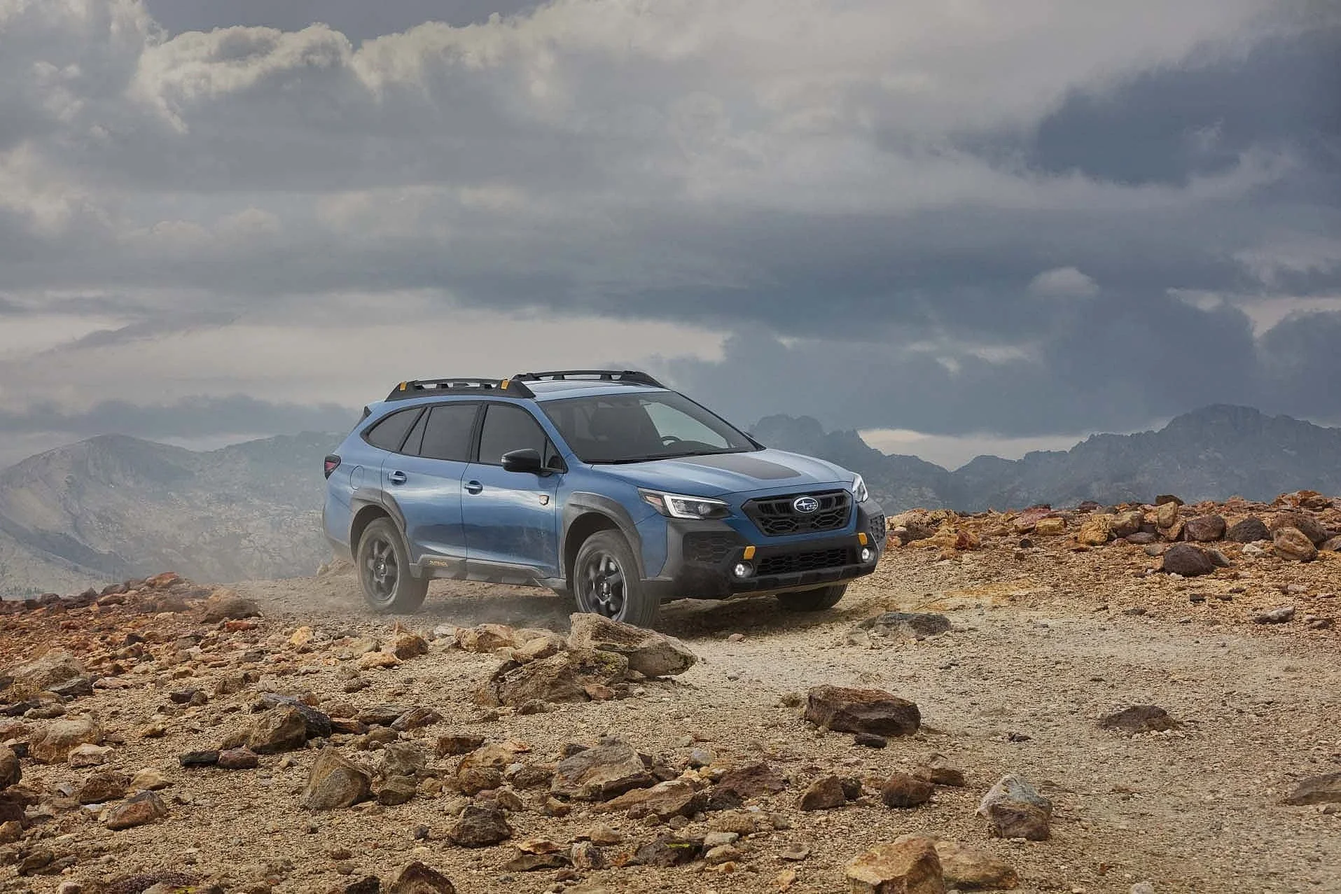A Subaru Outback Wilderness on rocky ground under a grey sky.