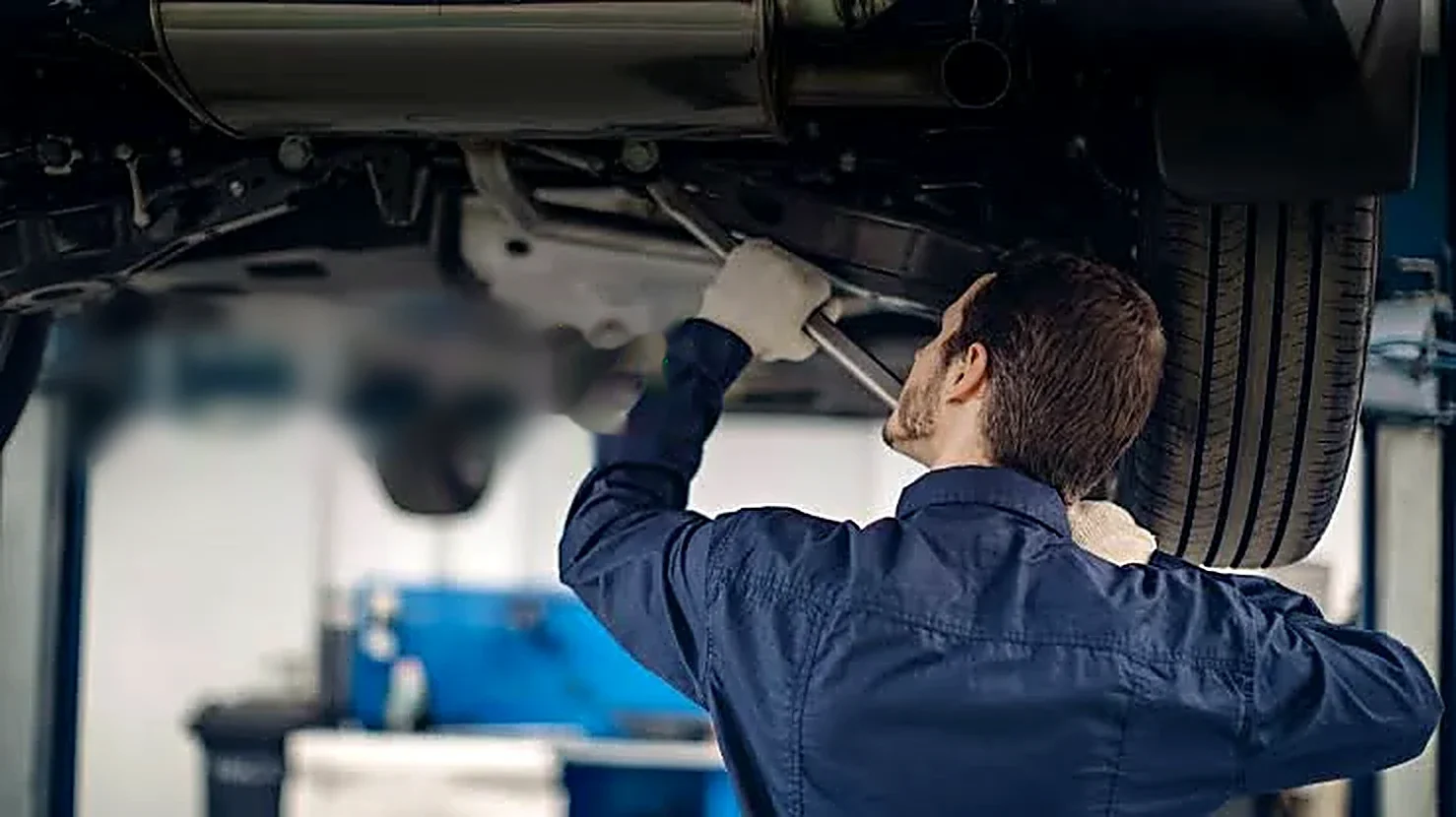 A technician working under a raised Subaru.