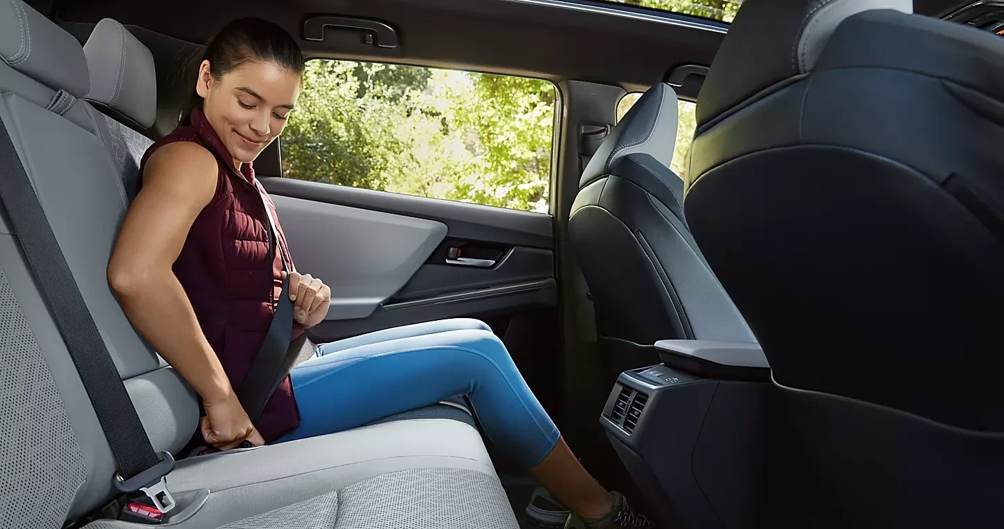 A woman buckling her seatbelt in the back seat of a Subaru Solterra.