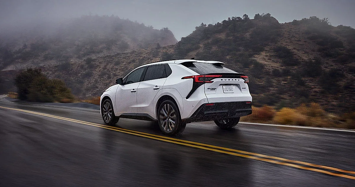 A white Subaru electric SUV on a wet mountain road.